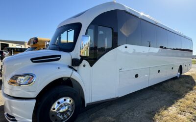 White charter bus parked on gravel.